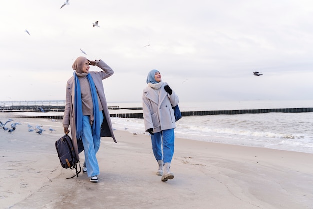 Two muslim female friends walking by the beach while traveling