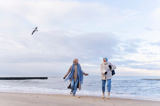 Two muslim female friends walking by the beach while traveling