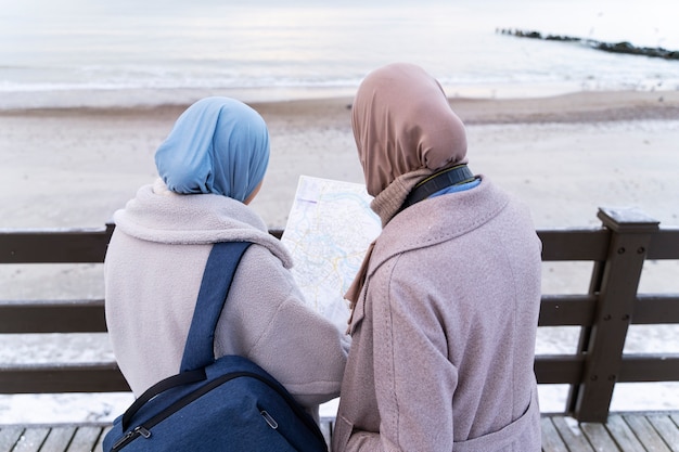 Two muslim women with hijabs consulting a map while traveling