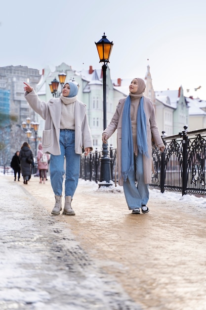 무료 사진 도시를 방문하는 동안 주위를 둘러보고 히잡을 쓴 두 명의 이슬람 여성