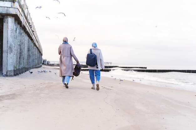 Two muslim women with hijabs taking a walk on the beach while traveling