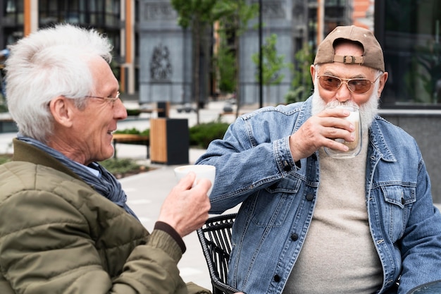 Two older men in the city having coffee together and chatting