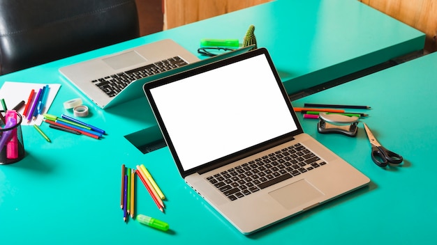 청록색 테이블에 화려한 문구와 함께 두 개의 열린 노트북