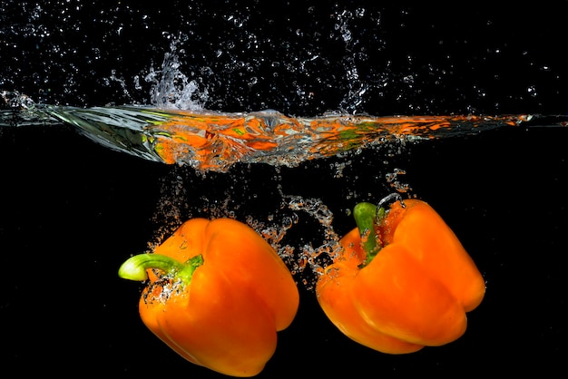 Two orange bell pepper floating under the water