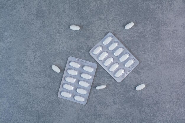 Две упаковки белых таблеток на мраморной поверхности