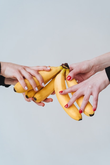 Free photo two pairs of hands holding a few bananas