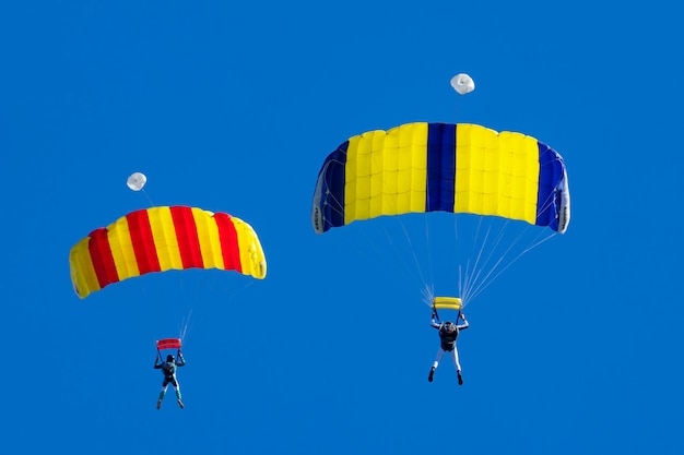 Free photo two parachutists against a blue sky