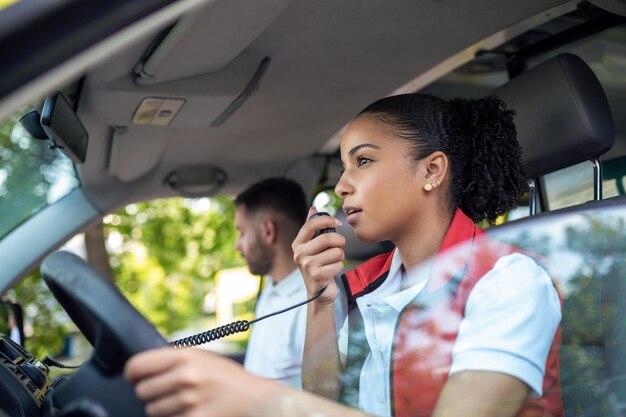 Два фельдшера в машине скорой помощи, афроамериканка-фельдшер за рулем и разговаривает по радио