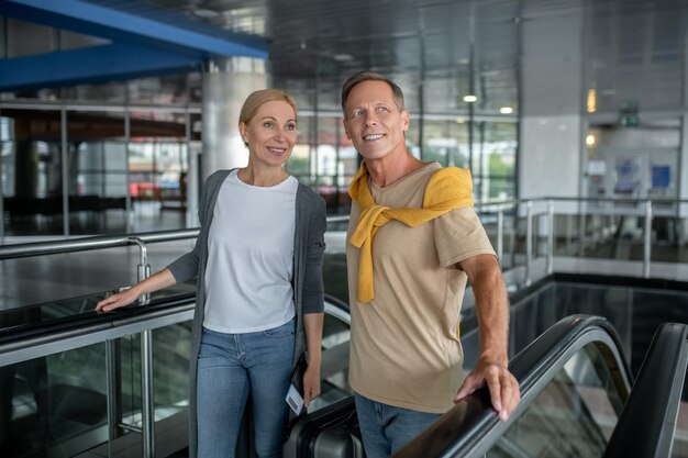 Два пассажира выходят из эскалатора аэропорта