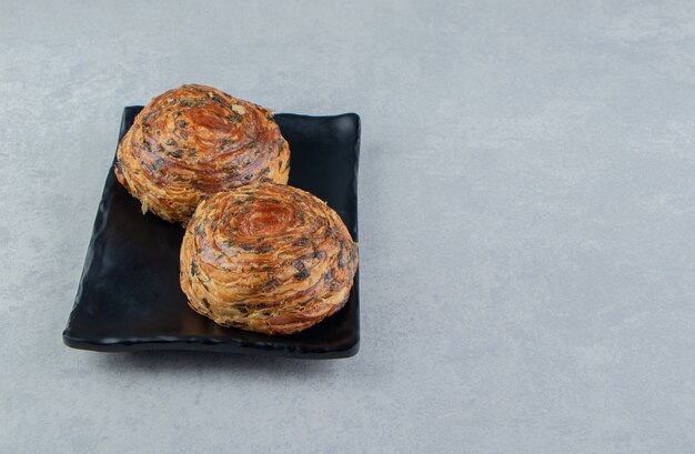 Two pastries with chocolate on dark plate. 