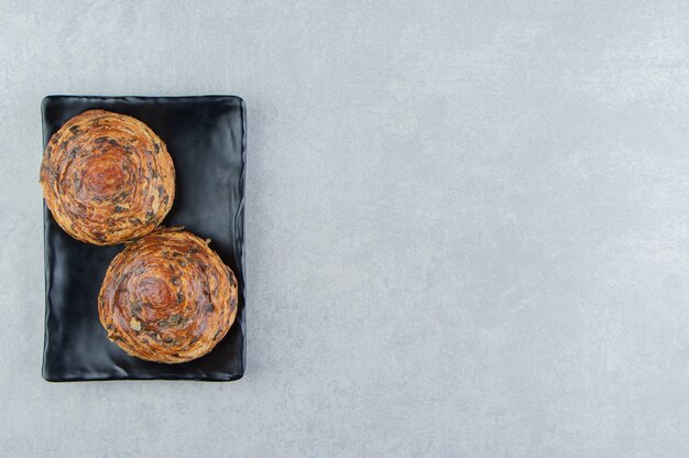 Two pastries with chocolate on dark plate. 