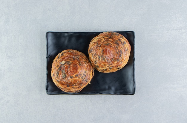 Two pastries with chocolate on dark plate. 