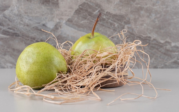 Two pears on a small straw pile on marble 