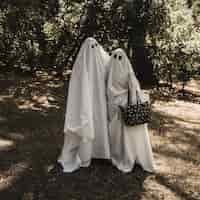 Free photo two people in ghost costumes hugging each other in forest