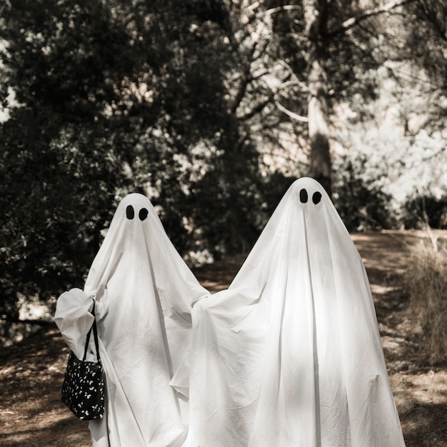 Free photo two people in ghost costumes walking in forest