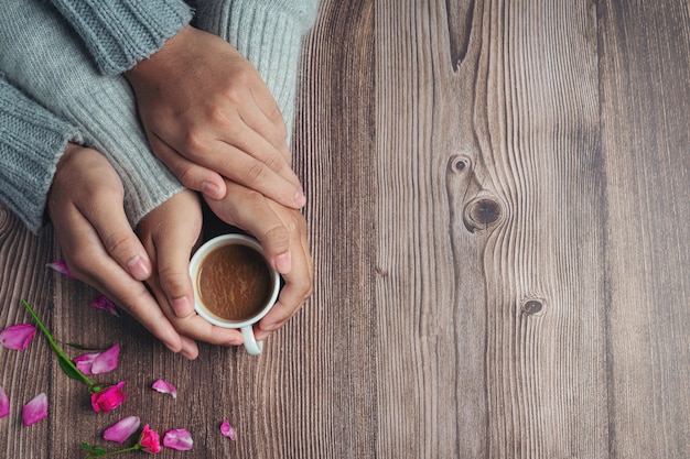 木製のテーブルに愛と暖かさを持って手にコーヒーのカップを保持している2人
