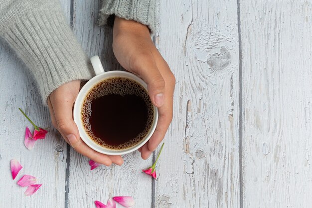 Two people holding cup of coffee in hands with love and warmth on wooden table