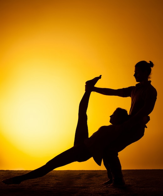 Два человека практикующих йогу в лучах заката