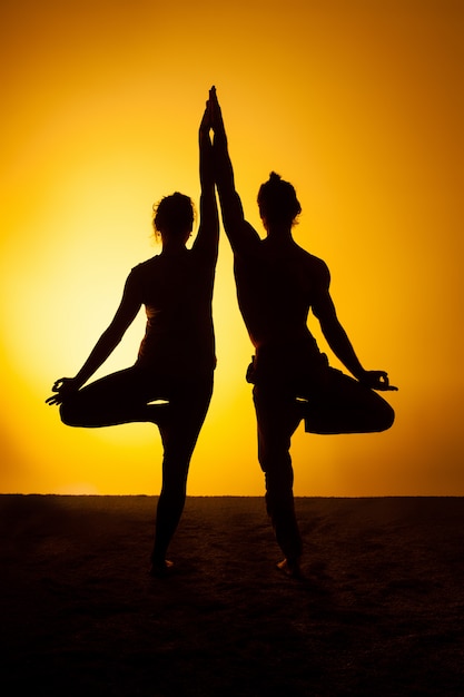 Free photo two people practicing yoga in the sunset light