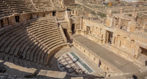 Two people standing in an ancient amphitheater during daytime