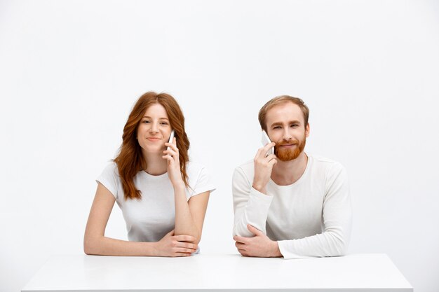 Two people talking mobile phone near each other