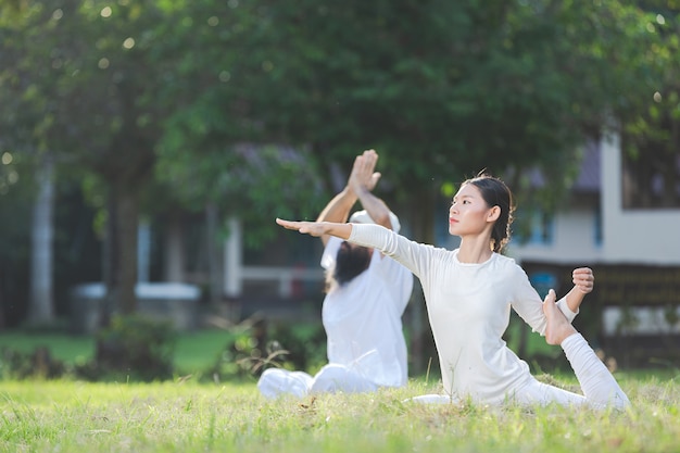 Two people in white outfit doing yoga in nature