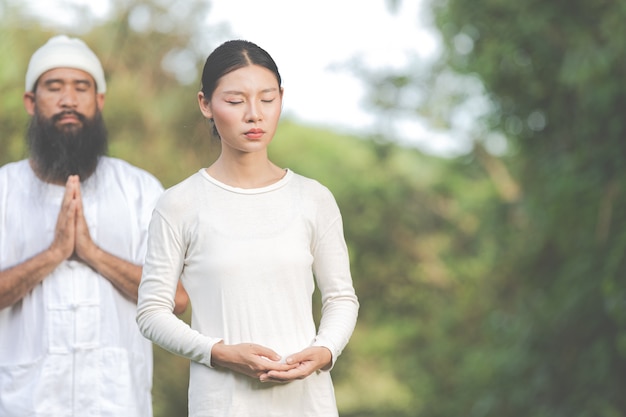 Two people in white outfit meditating in nature