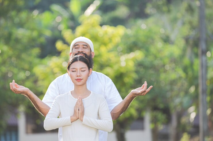 Free Photo two people in white outfit meditating in nature