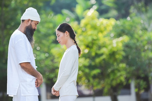 Two people in white outfit meditating in nature