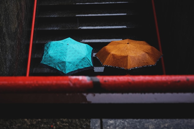 Two person holding teal and brown umbrellas