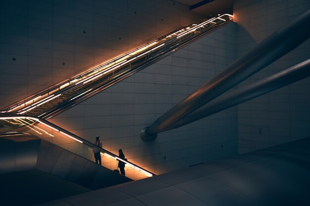 Two person standing on escalator