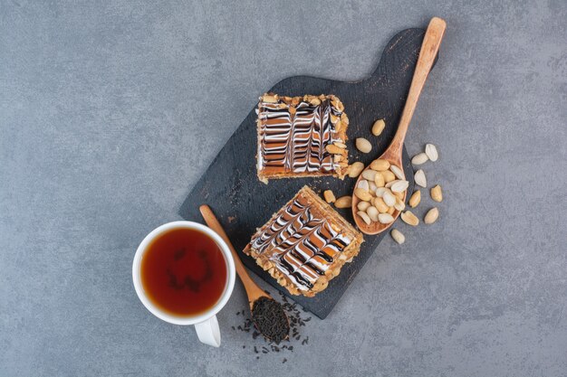 Two piece of cake on dark cutting board.