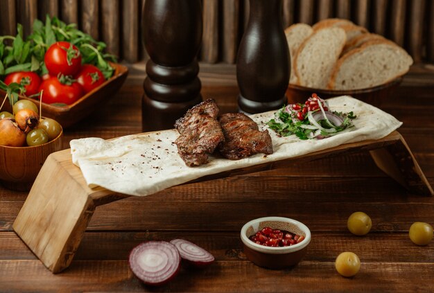 Two pieces of beef steaks served in lavash with species