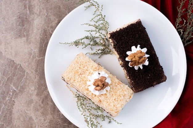 Two pieces of cake on white plate on marble surface