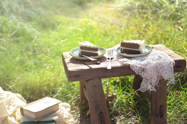 Two pieces of cake on wooden table outdoors