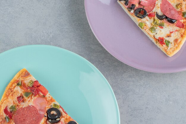 Two platters with pizza slices on marble 