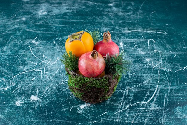 Two pomegranates with persimmon on marble.