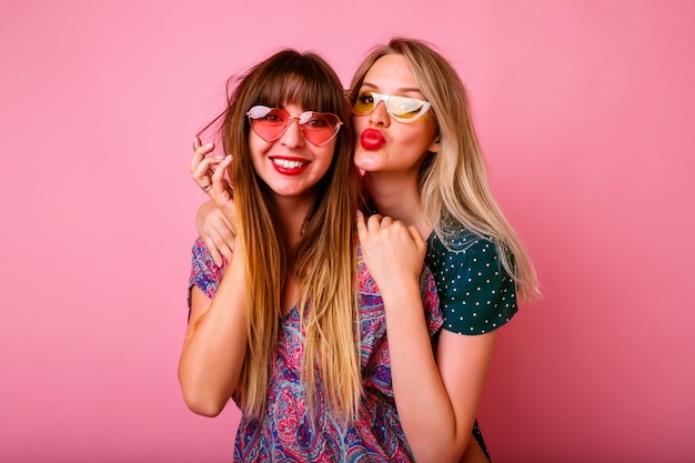 Two positive best friends having fun wearing sunglasses