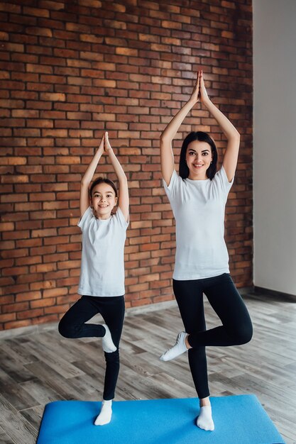 青いヨガマットで朝の運動をしている2人のかわいい姉妹。