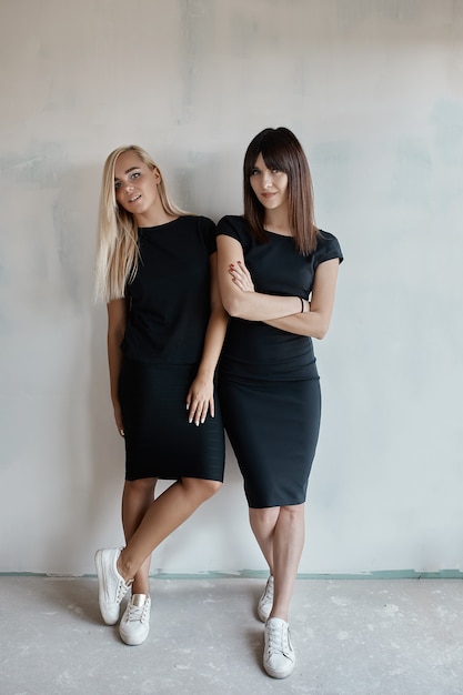 Two pretty woman in a black dress indoor