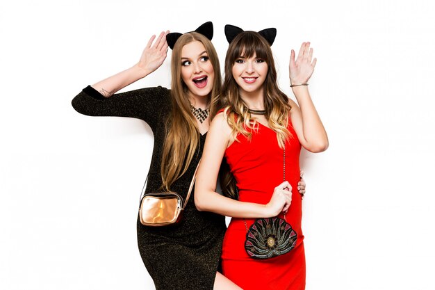Two pretty women in cat carnival ears and evening dress having fun