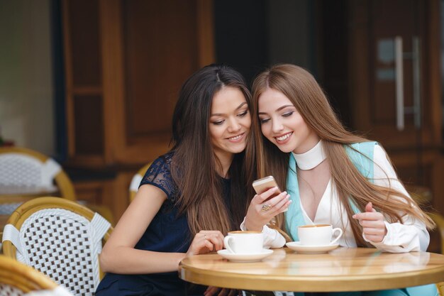 two pretty young women in cafe with coffee and phone