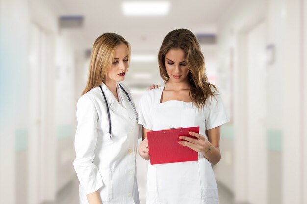 Two pretty young women doctors, nurses looking through the patient's medical record.
