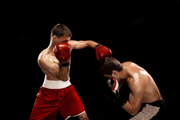 Two professional boxer boxing on black smoky background,