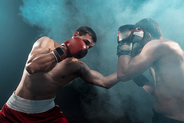 Two professional boxer boxing on black smoky space,