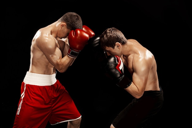 Два профессиональных боксера боксируют на черной стене