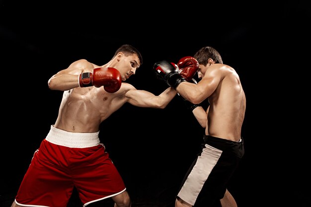 Два профессиональных боксера боксируют на черной стене