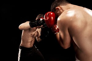 Free photo two professional boxer boxing on black wall