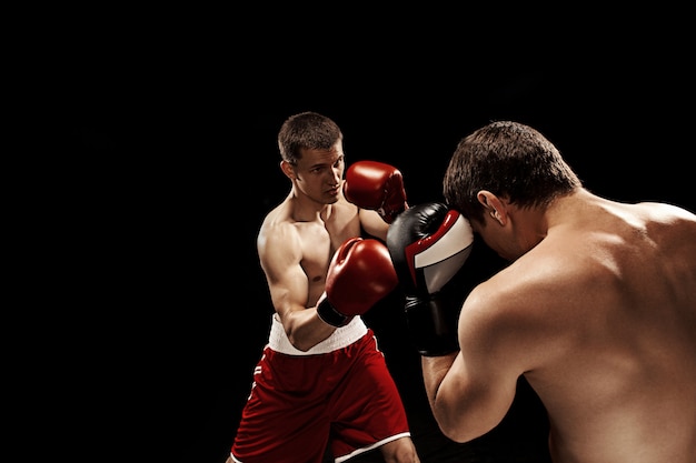 Two professional boxers boxing on black wall