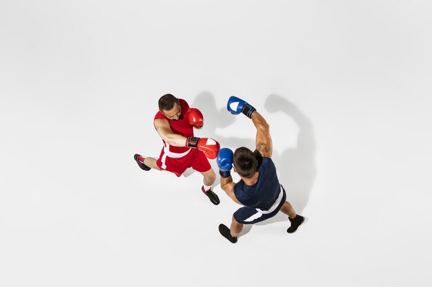 Two professional boxers boxing isolated on white studio background, action, top view. Couple of fit muscular caucasian athletes fighting.